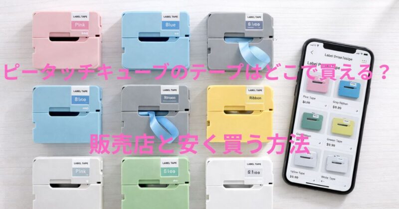 白い木製テーブルの上に、パステルカラーやリボンタイプのラベルプリンター用テープカートリッジが整然と並べられ、その横にはショッピングアプリで同じテープを表示したスマートフォンが置かれている、明るく清潔感のある上からの写真。